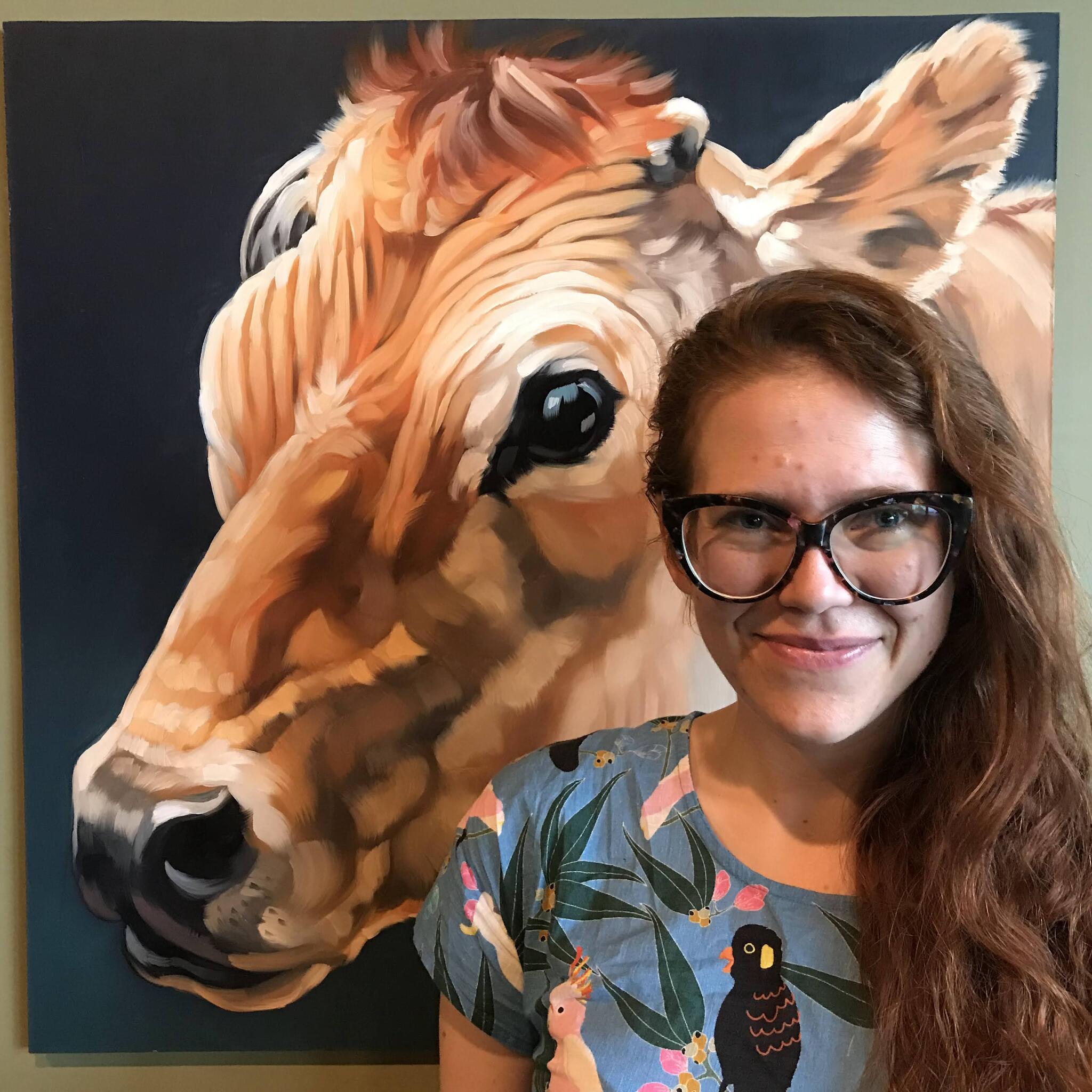 Serrin stands in front of a picture of a cow